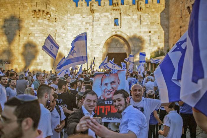 Ultranacionalistas israelíes ondean banderas y un cartel contra el primer ministro Naftali Bennett, durante la Marcha de las Banderas, ayer, cerca de la Ciudad Vieja de Jerusalén.
 · Foto: Ahmad Gharabli, AFP