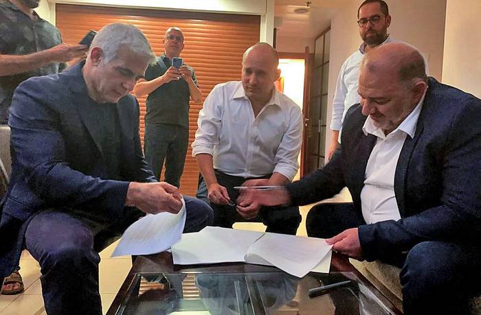 Raam Mansour Abbas (d), jefe del partido islámico árabe israelí, firma un acuerdo de coalición con el líder de la oposición israelí Yair Lapid (i) y el nacionalista de derecha Naftali Bennett, ayer, en Ramat Gan, cerca de la ciudad costera de Tel Aviv. · Foto:  Lista Árabe Unida Raam, AFP