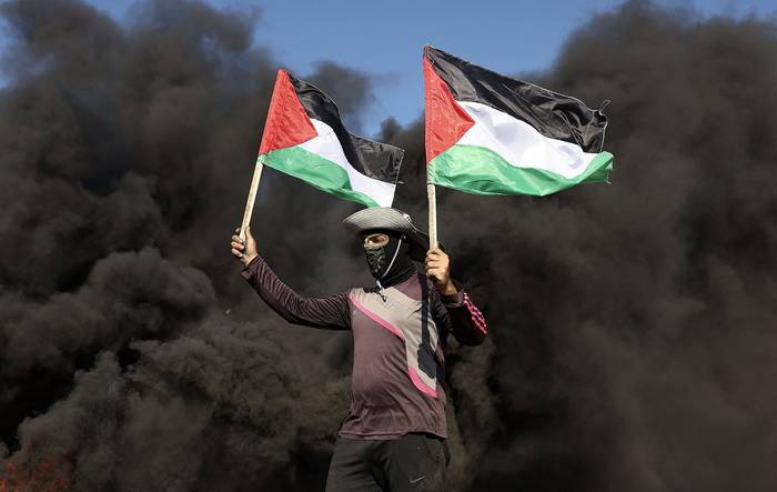 Un palestino junto a neumáticos en llamas durante una protesta en la valla fronteriza con Israel, ciudad de Yenín (03.07.2023). · Foto: Mahmud Jamones, AFP