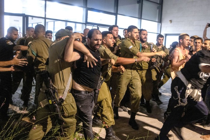 Soldados y policías israelíes se enfrentan a manifestantes de derecha después de que irrumpieran en la base militar de Beit Lid por la detención para interrogatorio de reservistas militares sospechosos de abusos. · Foto: Oren Ziv, AFP