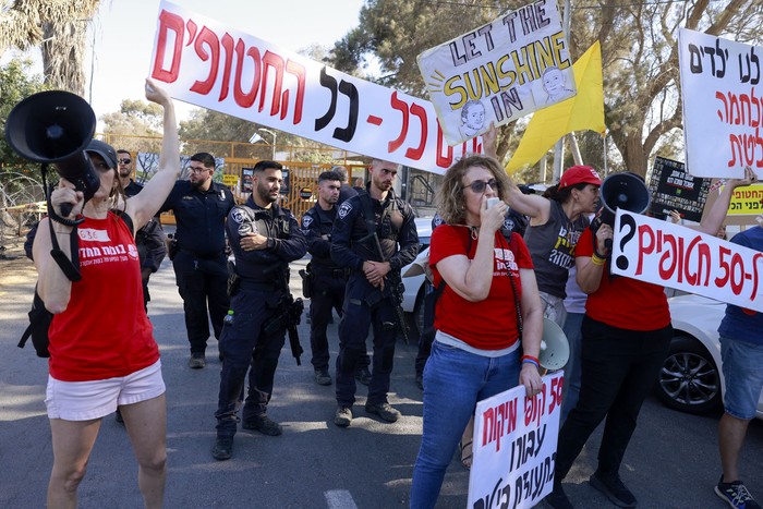 Policías vigilan a manifestantes que protestan contra la visita prevista del primer ministro israelí, Benjamin Netanyahu, el 3 de junio, al kibutz Nir Oz. · Foto: Menahen Kahana, AFP