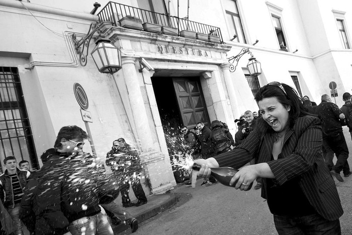 Una mujer descorcha una botella para celebrar el arresto del jefe mafioso Michele Zagaria, a las puertas de la comisaria de Caserta. El paradero de Zagaria, condenado a cadena perpetua por asociacion mafiosa,
homicidio, posesion ilegal de armas y extorsion, se desconocia desde 1995. Fue localizado en un bunker bajo una casa en la que siempre fue su localidad de residencia, Casapesenna. · Foto: Efe, Cesare Abbate