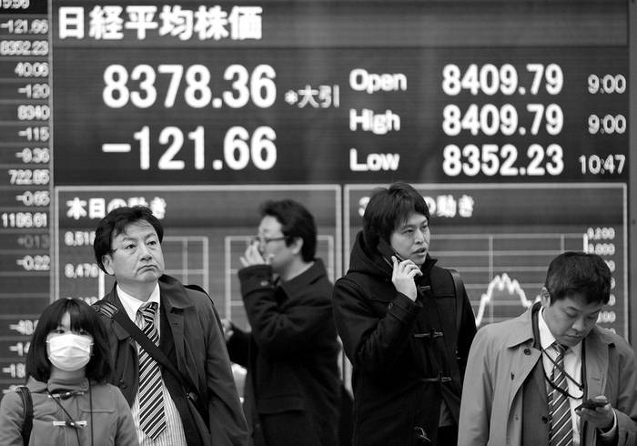 Personas pasan por delante de un monitor con el valor de cierre del indice Nikkei, en Tokio, el lunes. · Foto: Efe, Franck Robichon