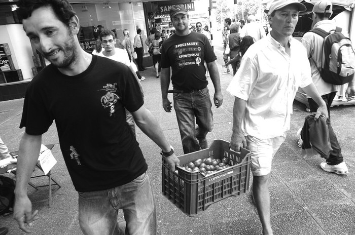 Trabajadores de Copronec caminan por la avenida 18 de Julio, en el centro de Montevideo, regalando tomates.  · Foto: Sandro Pereyra