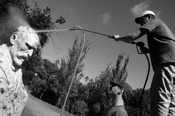 Maximiliano Trinchitella y Rodrigo Jubin, integrantes de la cooperativa Alborada, realizan tareas de limpieza de graffitis sobre el monumento al Dr E. Roux en el parque Rodó. · Foto: Nicolás Celaya