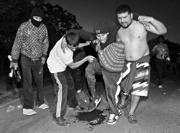 Unos hombres asisten a una persona que resultó herida en los enfrentamientos entre los ocupantes
de un parque público con los habitantes de los barrios cercanos, el viernes, en el barrio de Villa Soldati, en Buenos Aires. · Foto: Efe, Martín Quintana