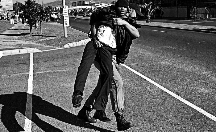 Un agente de la policía sudafricana arresta a un empleado de seguridad del estadio Green Point, en Ciudad del Cabo, Sudáfrica, que se manifestaba ayer junto a centenares de compañeros para exigir el pago de sus salarios. · Foto: EFE, s/d de autor