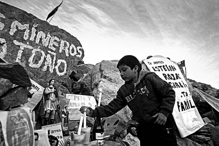 Un niño enciende una vela en un altar del campamento de la mina San José, el martes 24 de agosto de 2010, cerca de Copiapó,
a unos 830 kilómetros de Santiago, tras conocerse la noticia de que los mineros atrapados bajo tierra se encontraban con vida · Foto: Efe, Claudio Reyes