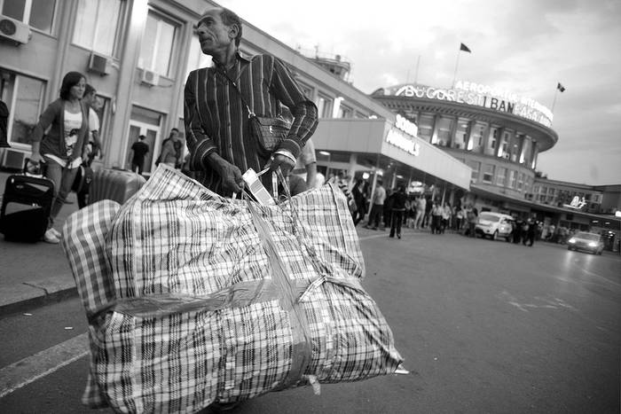 Un gitano rumano carga con su equipaje en el aeropuerto de Bucarest después de ser deportado de Francia. · Foto: efe, Mihai Barbu