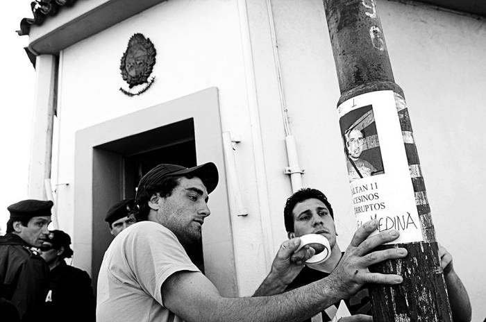 Amigos del joven Maiquel Martinho, asesinado el domingo en Piriápolis, colocan carteles con la foto de uno de los policías involucrados en el homicidio, ayer, frente a la sede judicial en la ciudad de Maldonado. · Foto: Nicolás Celaya