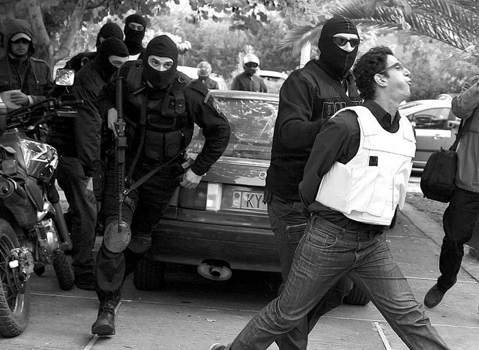 Miembros de las unidades antiterroristas trasladan a uno de los dos hombres arrestados como implicados en el envío de paquetes bomba a diversas embajadas en Atenas durante los dos últimos días.  · Foto: Efe, Simela Pantzartzi