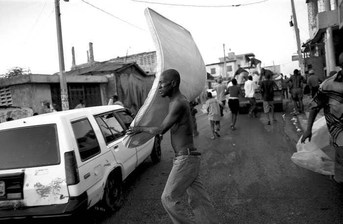 Haitianos recogen colchones que han sido repartidos tras la visita al campo de desplazados de Champ de Mars del candidato presidencial Yves Cristalin, de la Organización LAVNI, en Puerto Príncipe, el martes. · Foto: Efe, Andrés Martínez Casares