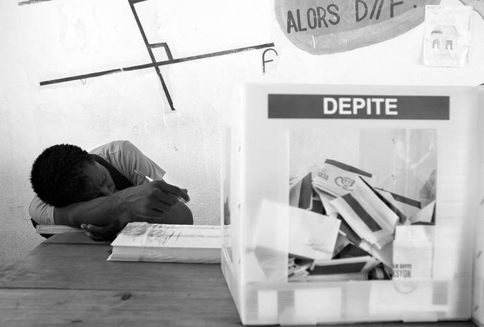 Un juez de mesa descansa mientras espera por votantes en un colegio electoral del sector de Cité Soleil, en Puerto Príncipe.
 · Foto: Efe, Orlando Barría