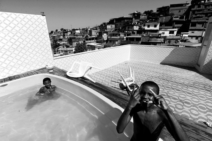 Niños se refrescan en una piscina de la mansión construida por Luciano Martiniano da Silva, Pezão, acusado de narcotráfico, en una de las favelas del Complexo do Alemão,
en Río de Janeiro, ocupadas por centenares de policías y militares.  · Foto: EFE, Fernando Bizerra Jr