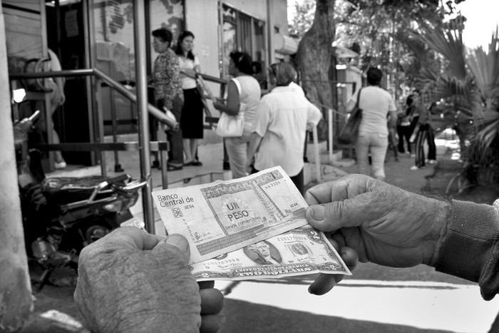 Un hombre muestra un peso convertible cubano y dos dólares estadounidenses frente a una oficina
de Western Union en La Habana, el lunes.  · Foto: Efe, Rolando Pujol