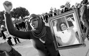 Una mujer muestra una imagen de Gadafi frente a la fortaleza de Bab Al Azizia, en Trípoli,
durante una manifestación en apoyo al líder libio. 