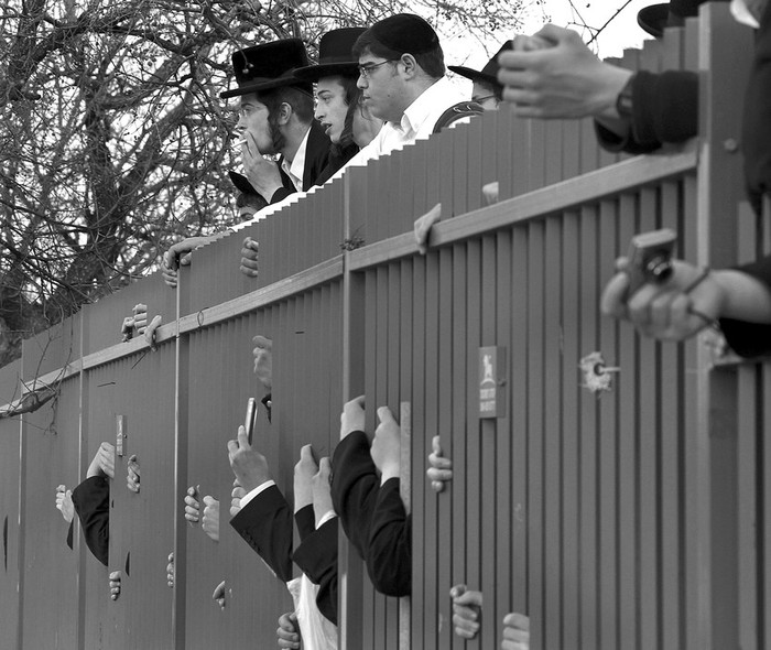 Judíos ultraortodoxos observan desde una valla tras la explosión de un artefacto en el interior de un ómnibus, en Jerusalén.
 · Foto: EFE, Jim Hollander 