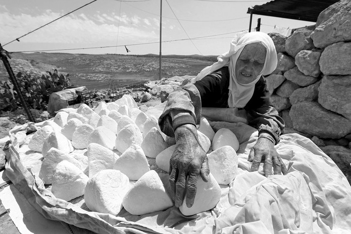 Una mujer palestina acomoda queso artesanal en el poblado de Yatta, Cisjordania. Unas 90 personas viven en la zona, muy próxima al
muro de separación en la zona de Hebrón. La población vive del ganado y de los productos que elaboran y venden en Hebrón. El Ejército
israelí no les permite levantar viviendas y por ello viven en cuevas acondicionadas.  · Foto: Efe, Abed Al Hashlamoun