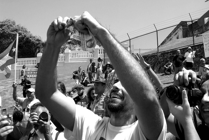 Un joven puertorriqueño se deshace de varios billetes de dólar como protesta por la visita del presidente Barack Obama en el Viejo San
Juan, donde miles de personas, independentistas y anexionistas, se congregan para manifestarse. · Foto: Efe, Jorge Muñiz