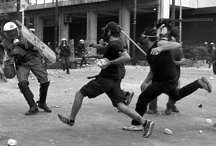 Disturbios entre manifestantes y policías ante el Parlamento griego, durante la segunda jornada de protestas de la huelga general contra el nuevo plan de ajuste aprobado por el Parlamento, en Atenas.  · Foto: Efe, Orestis Panagiotou