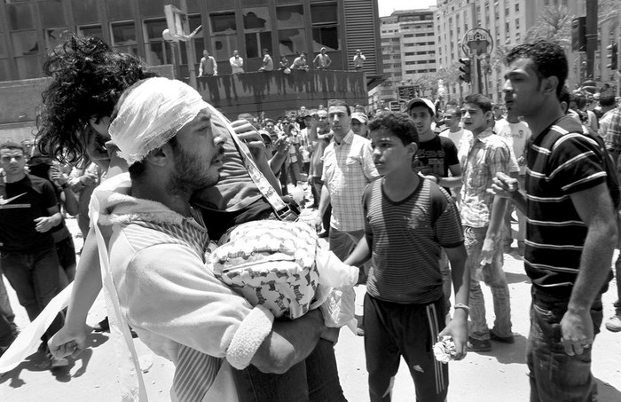 Un hombre ayuda a un joven herido durante un choque entre la policía y manifestantes, en la plaza Tahrir de El Cairo.  · Foto:  foto: Efe, Andre Pain