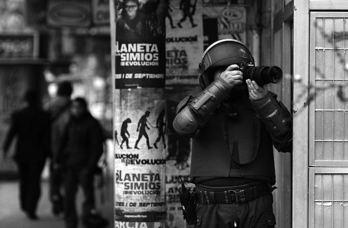 Un policía antimotines fotografía a manifestantes durante una protesta en Santiago de Chile, en el marco de la primera jornada de paro nacional de dos días convocado por la Central Unitaria de Trabajadores (CUT).
 · Foto: Efe, Mario Ruiz