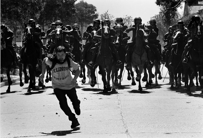 Un manifestante corre durante los disturbios que se registraron ayer en las inmediaciones del Cementerio General de Santiago de Chile, donde culminaba la marcha que agrupaciones de derechos humanos, estudiantes y
dirigentes políticos realizaron con motivo de los 38 años del golpe militar de 1973. · Foto: Efe, Felipe Trueba