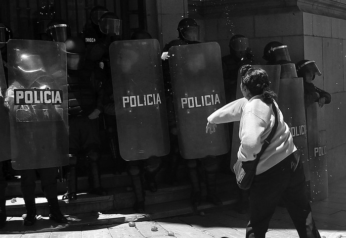 Una mujer lanza tomates a la policía boliviana frente a la sede de la vicepresidencia ayer,
durante una marcha de protesta de activistas en contra de la intervención de la marcha indígena. · Foto: EFE, Martín Alipaz