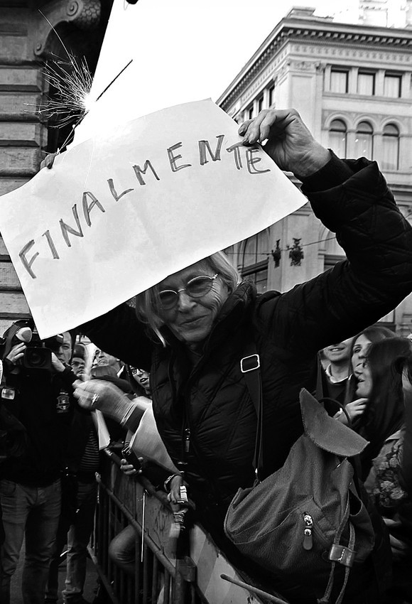 Una mujer muestra un cartel con un mensaje alusivo a la dimision de
Silvio Berlusconi, en el exterior del Palacio Chigi, en Roma. · Foto: Efe, Alessandro Di Meo