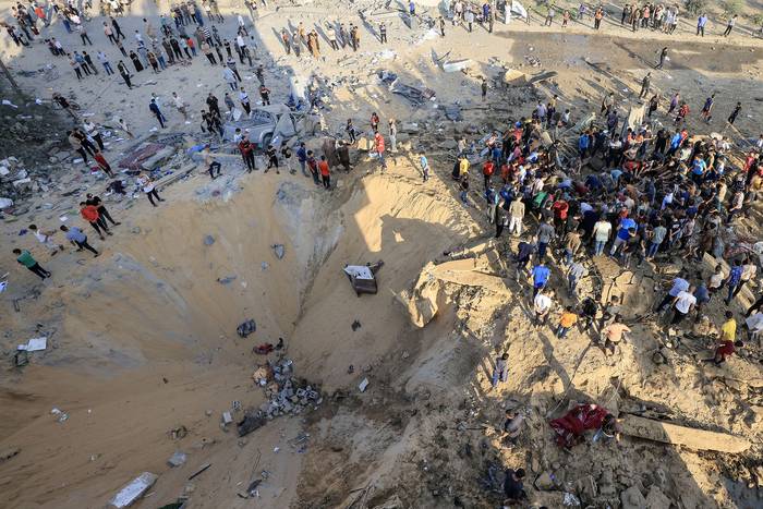 Palestinos junto a un cráter causado por una explosión de un ataque aéreo israelí en Khan Yunis, en el sur de la Franja de Gaza (16.10.2023). · Foto: Mahmud Hams, AFP
