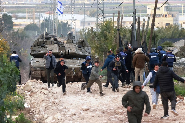 Niños y periodistas palestinos se dispersan cuando los tanques israelíes ingresan al campamento de refugiados palestinos, el 23 de febrero, en Yenín, en la Cisjordania ocupada. · Foto: Jaafar Ashtiyeh / AFP