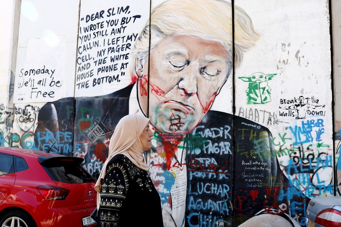 Una mujer palestina pasa junto a un mural que representa a Donald Trump en el muro de separación de Israel, el 5 de noviembre, en Belén, en la Cisjordania ocupada. · Foto: Hazem Bader, AFP