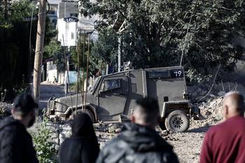 Vehículo militar israelí estacionado frente al cementerio de los mártires, mientras palestinos intentan visitar las tumbas de sus familiares, el 30 de marzo, en el campo de refugiados de Yenín, en la Cisjordania ocupada. · Foto: Mohammed Mansour, AFP