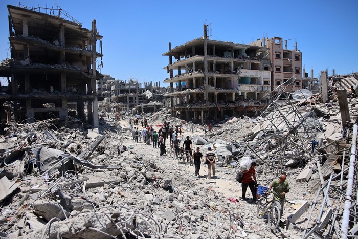 Palestinos cargan algunas pertenencias recuperadas mientras abandonan el campo de refugiados de Jabalia, Franja de Gaza. · Foto: Omar Al-Qattaa, AFP