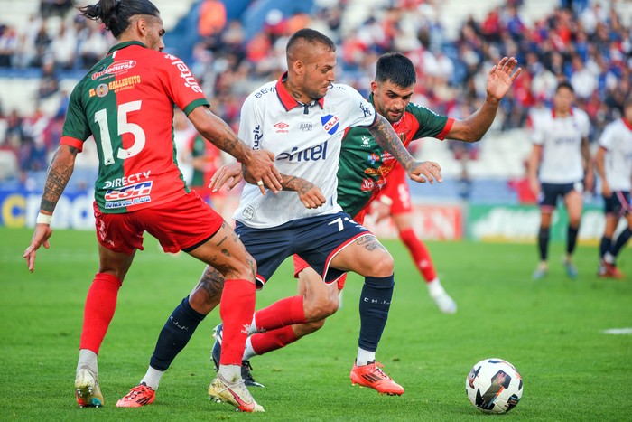 Nicolás López, de Nacional, entre Ayrton Cougo y Mauricio Viera, de Boston River, el 1º de diciembre, en el Gran Parque Central. · Foto: Gianni Schiaffarino