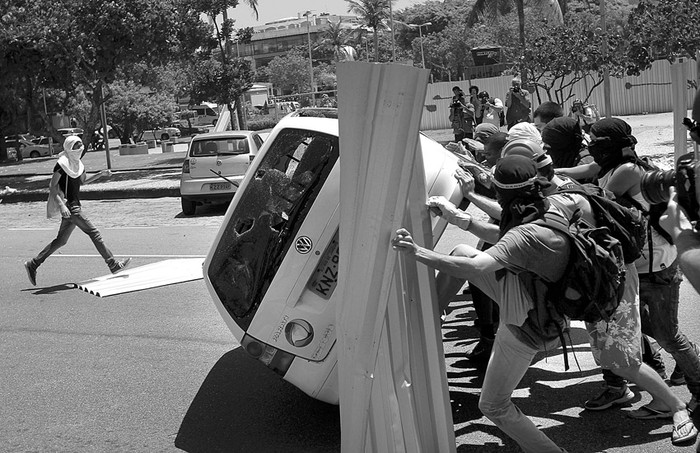 Manifestantes voltean un vehículo de la Televisión Record, cerca del hotel donde se hizo la subasta del yacimiento Libra, ayer, en la playa de Barra da Tijuca en Río de Janeiro (Brasil). · Foto: Marcelo Sayão, Efe