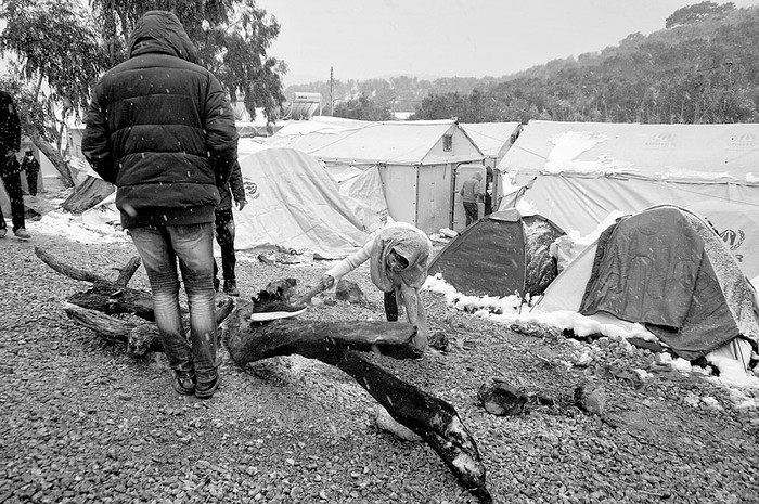 Emigrantes encienden fuego durante una nevada, el lunes, en la isla griega de Lesbos. Foto: afp, s/d de autor