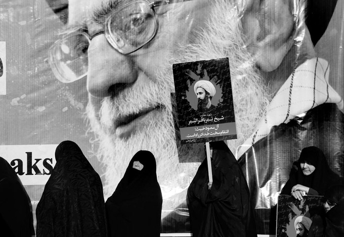 Una mujer iraní muestra un cartel del clérigo chiita Nimr Baqir al Nimr delante de un cartel gigante del líder supremo iraní, ayatolá Ali Jamenei, durante una protesta, ayer en Teherán, Irán. Foto: Abedin Taherkenareh, Efe