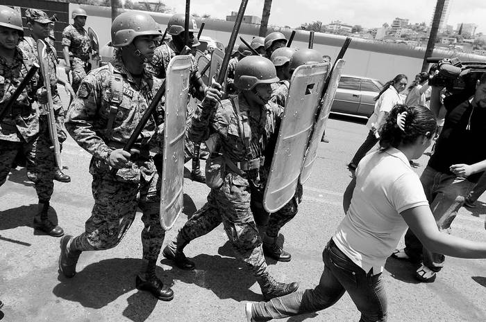 Militares hondureños desalojan a un grupo de manifestantes del Frente Nacional de Resistencia Popular en el portón principal de acceso a la sede de la presidencia, donde se realiza el acto de la instalación de la Comisión de la Verdad y reconciliación de Honduras · Foto: EFE, Gustavo Amador