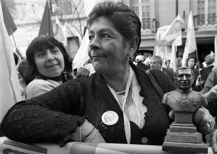 Una mujer porta una estatuilla del ex dictador Augusto Pinochet mientras la candidata presidencial de la derecha chilena, Evelyn Matthei, inscribe su candidatura, el domingo 18, en el Servicio Electoral, en Santiago de Chile. · Foto: Mario Ruiz, Efe