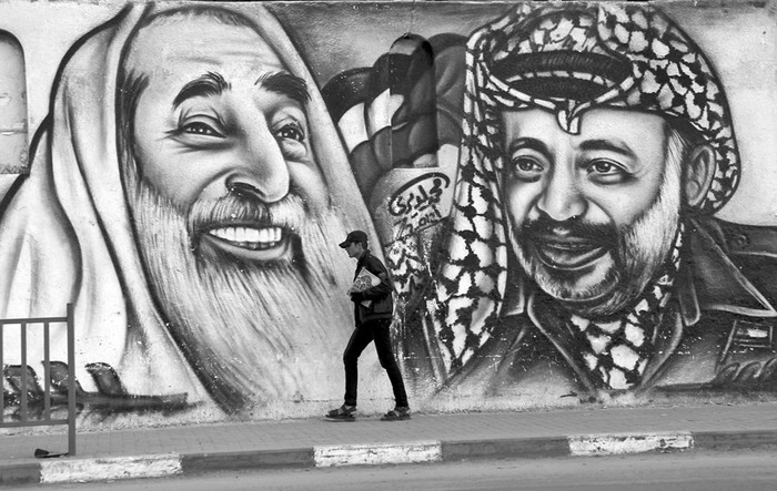 Un hombre camina junto a un mural en donde aparece el líder del grupo islamista palestino Hamas, Jaled Meshal, y el histórico líder palestino Yasser Arafat, en la ciudad de Gaza.  · Foto: Mohamed Saber, Efe