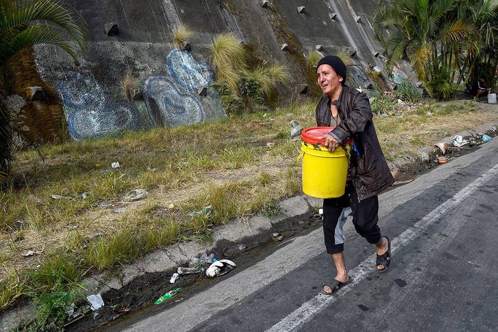 Una persona transporta agua de manantial para usar en su inodoro, ayer, en el vecindario de Petare, en Caracas. · Foto: Federico Parra
