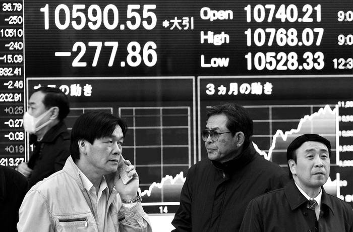 Hombres de negocios japoneses junto a un panel electrónico que muestra los valores de la Bolsa en el centro de Tokio, el viernes.  · Foto: Efe, Everett Kennedy Brown