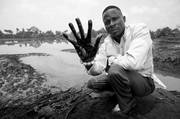 Fotografía sin fechar que muestra al granjero Eric Dooh con su mano cubierta de petróleo en el arroyo Goi, en Ogoniland, Nigeria. / foto: