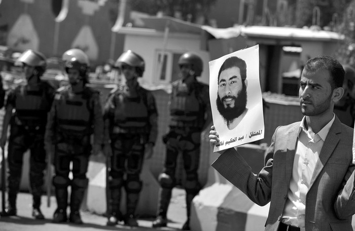 Un familiar del prisionero yemení en Guantánamo Abdul Hakeem Kalib sujeta una imagen de Abdul durante una protesta en la que piden la liberación de los presos yemeníes en la base naval de Estados Unidos, frente a la embajada de ese país, en Saná, Yemen.  · Foto:  Mohammed Hamoud, Efe