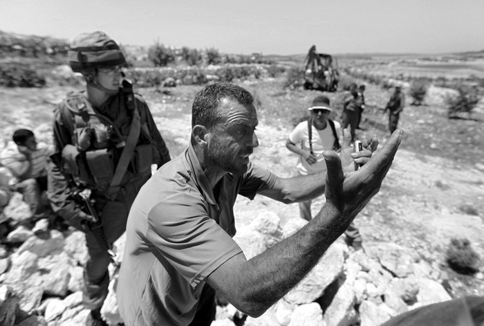 Un ciudadano palestino gesticula ante soldados israelíes después de que sus pozos de agua fuesen destruidos y sus olivos talados, en un campo cerca de la frontera con Israel, en la ciudad cisjordana de Beit Jala, cerca de Hebrón, el lunes.  · Foto:  Abed Al Hashlamoun, Efe