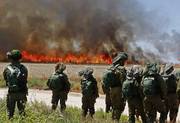 Soldados israelíes observan un incendio en un campo de trigo, provocado por manifestantes palestinos, ayer, cerca del kibutz de Nahal Oz.
