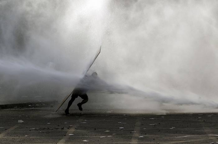 Un manifestante es alcanzado por un cañón de agua de la policía antidisturbios, durante una protesta contra el gobierno en Santiago de Chile, el 18 de noviembre.  · Foto: Claudio Reyes, AFP