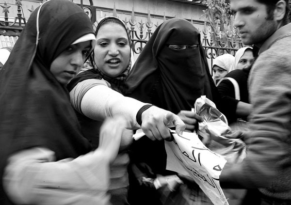 Un voluntario registra los bolsos de varias manifestantes egipcias, ayer, en un puesto de control montado por civiles en uno de los accesos
a la plaza Tahrir en El Cairo (Egipto).  · Foto: Efe, André Pai