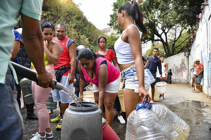 Reparto de agua potable por miembros de la Policía Nacional Bolivariana, ayer, en el vecindario de San Agustín, en Caracas. · Foto: Yuri Cortez / AFP